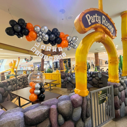 Decorated birthday party room with balloons and archway in a mall setting