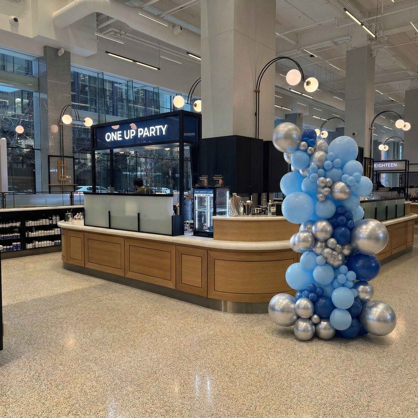 Decorative balloon arch with blue and silver balloons in a modern indoor setting.