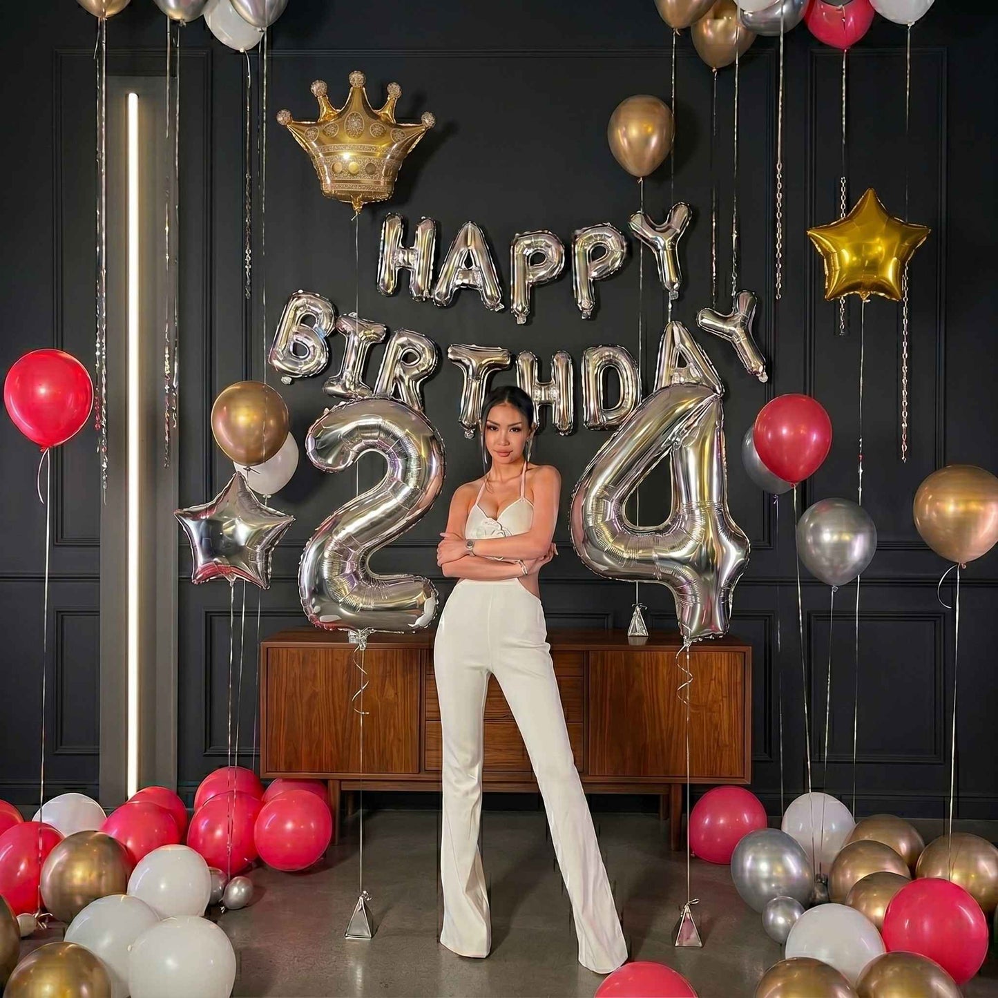 Person standing in a room decorated with 'Happy Birthday 24' balloons and colorful balloons.