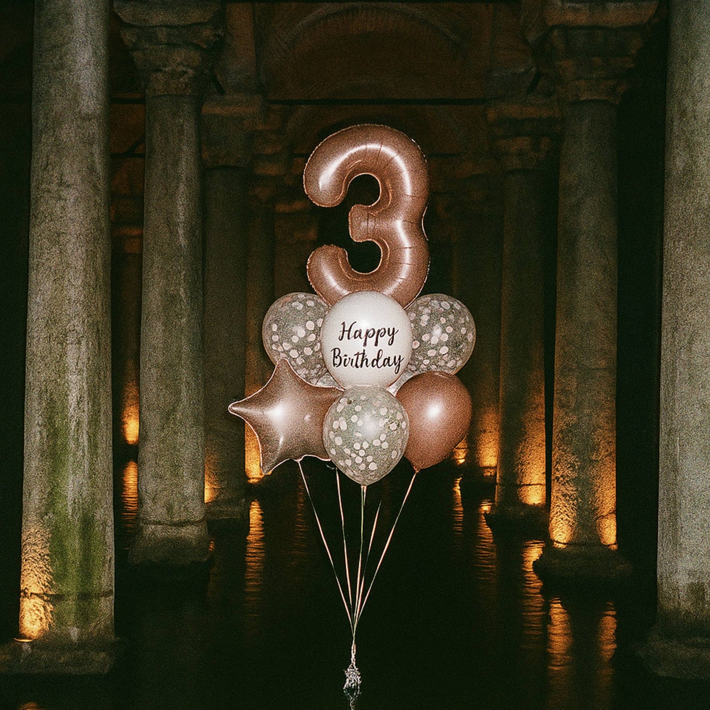 Balloon bouquet with number '3' and 'Happy Birthday' text in a stone archway setting