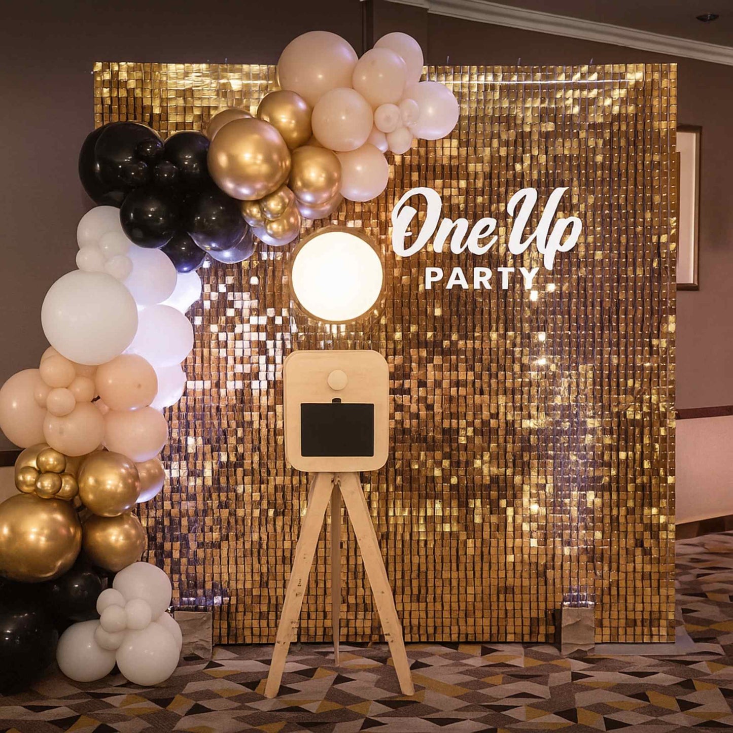 Decorative setup with balloons and a 'One Up Party' backdrop