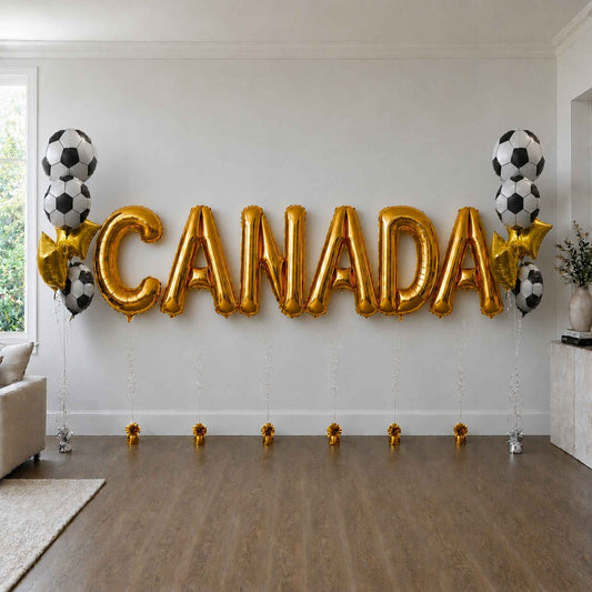 Gold 'CANADA' balloons with soccer ball designs on a white wall.