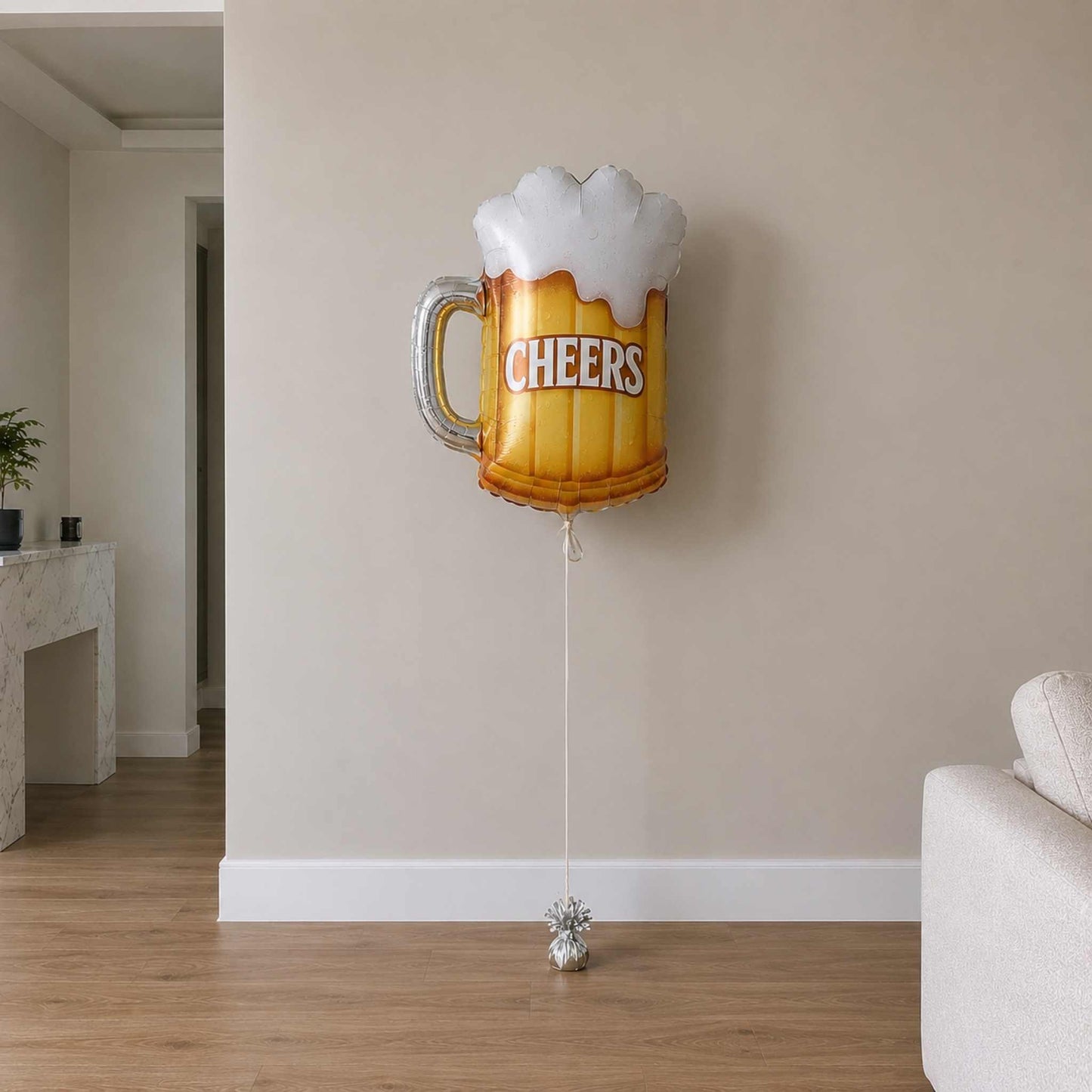 Beer mug balloon with 'Cheers' text in a room with a couch and plant.