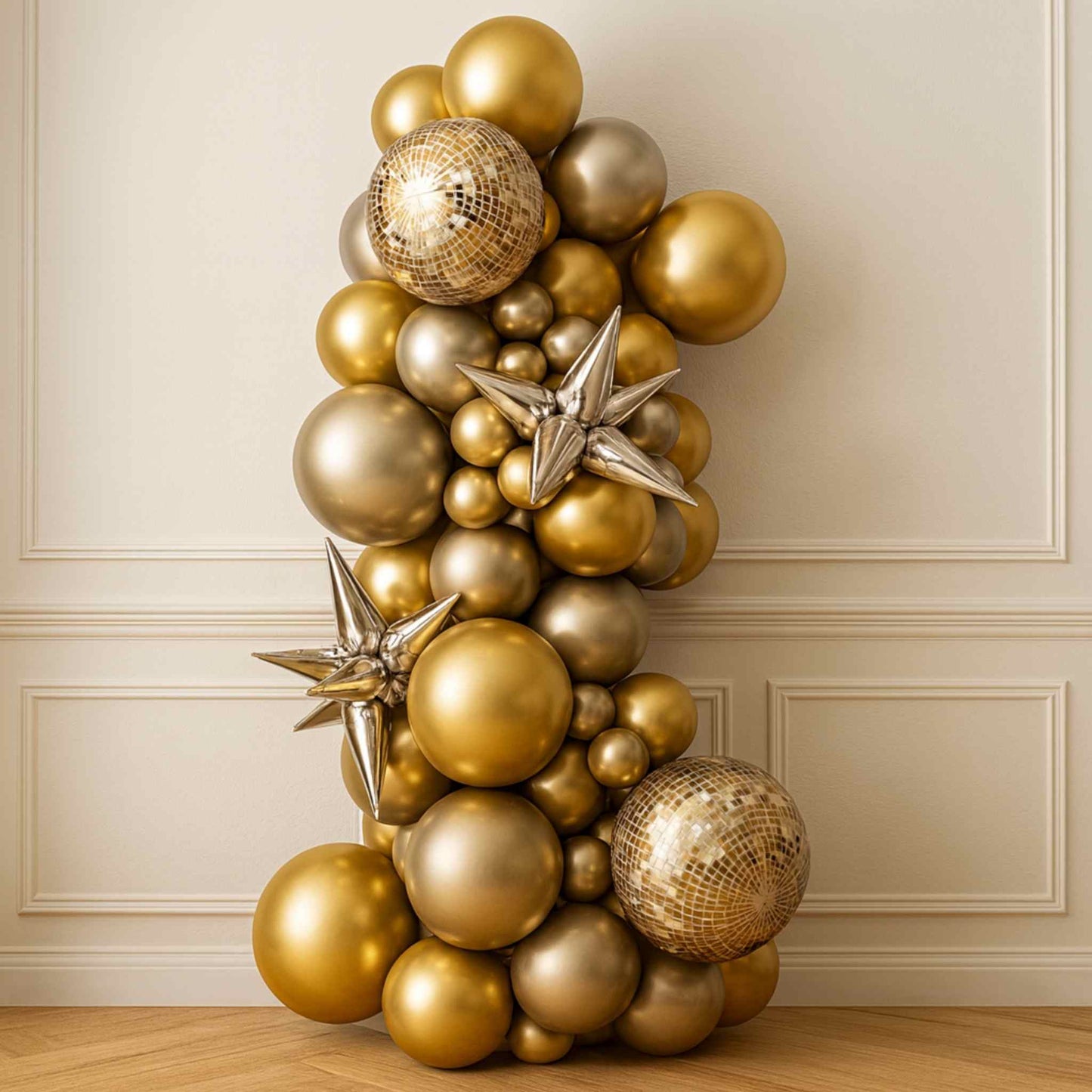 Gold and silver balloon arch against a beige wall
