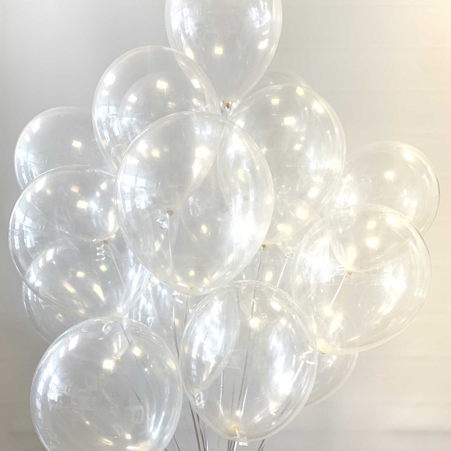 Clear balloons helium filled against a white background with silver ribbon.