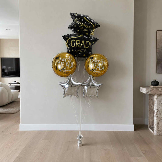 Graduation-themed balloons in black, gold, and silver in a living room setting.