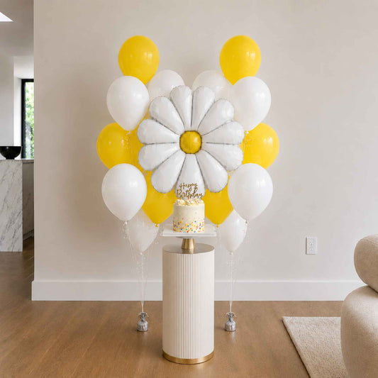 Decorative balloon arch with a cake on a pedestal in a room setting.