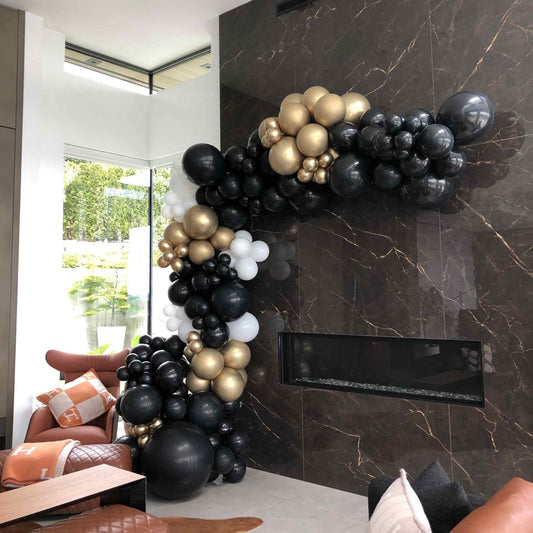 Balloon arch in a modern living room with a marble wall.