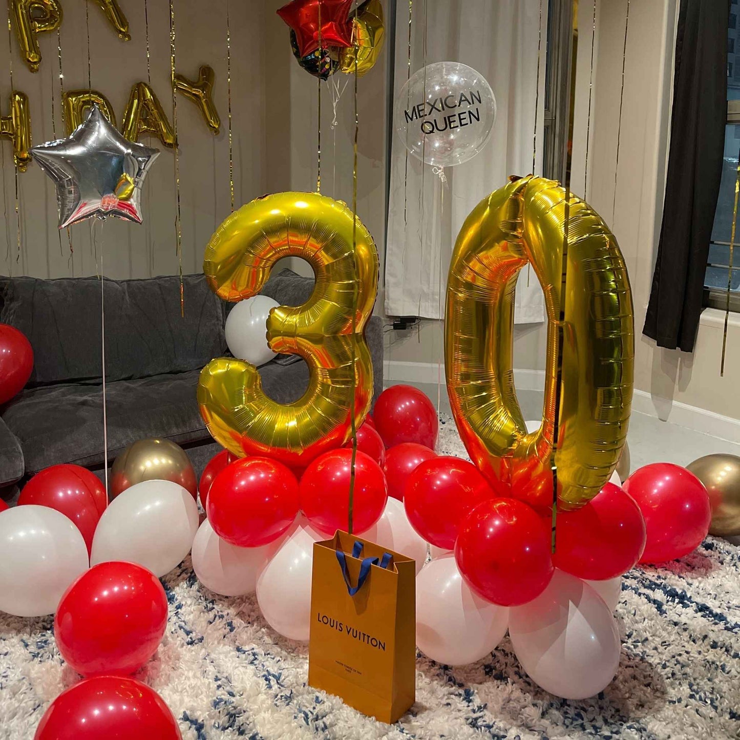 Gold '30' balloons with red and white balloons on a carpeted floor.