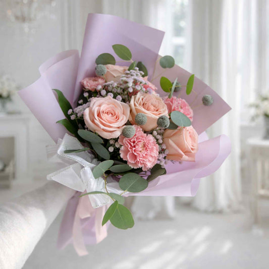 Bouquet of pink and green flowers wrapped in purple paper on a white background