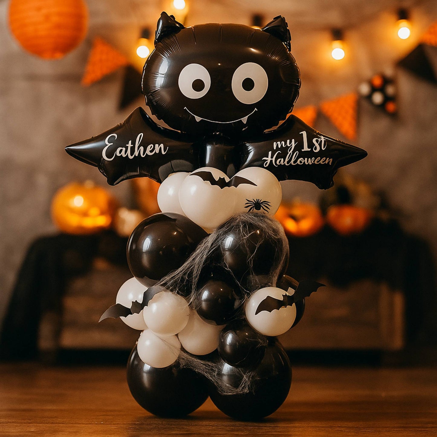 Halloween-themed balloon arrangement with a bat design and text, set against a festive background.