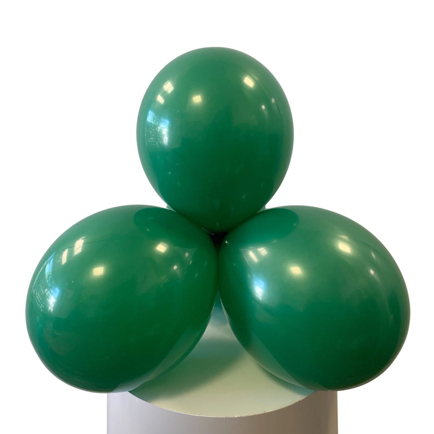 Three green balloons stacked on a white cylindrical base with a white background