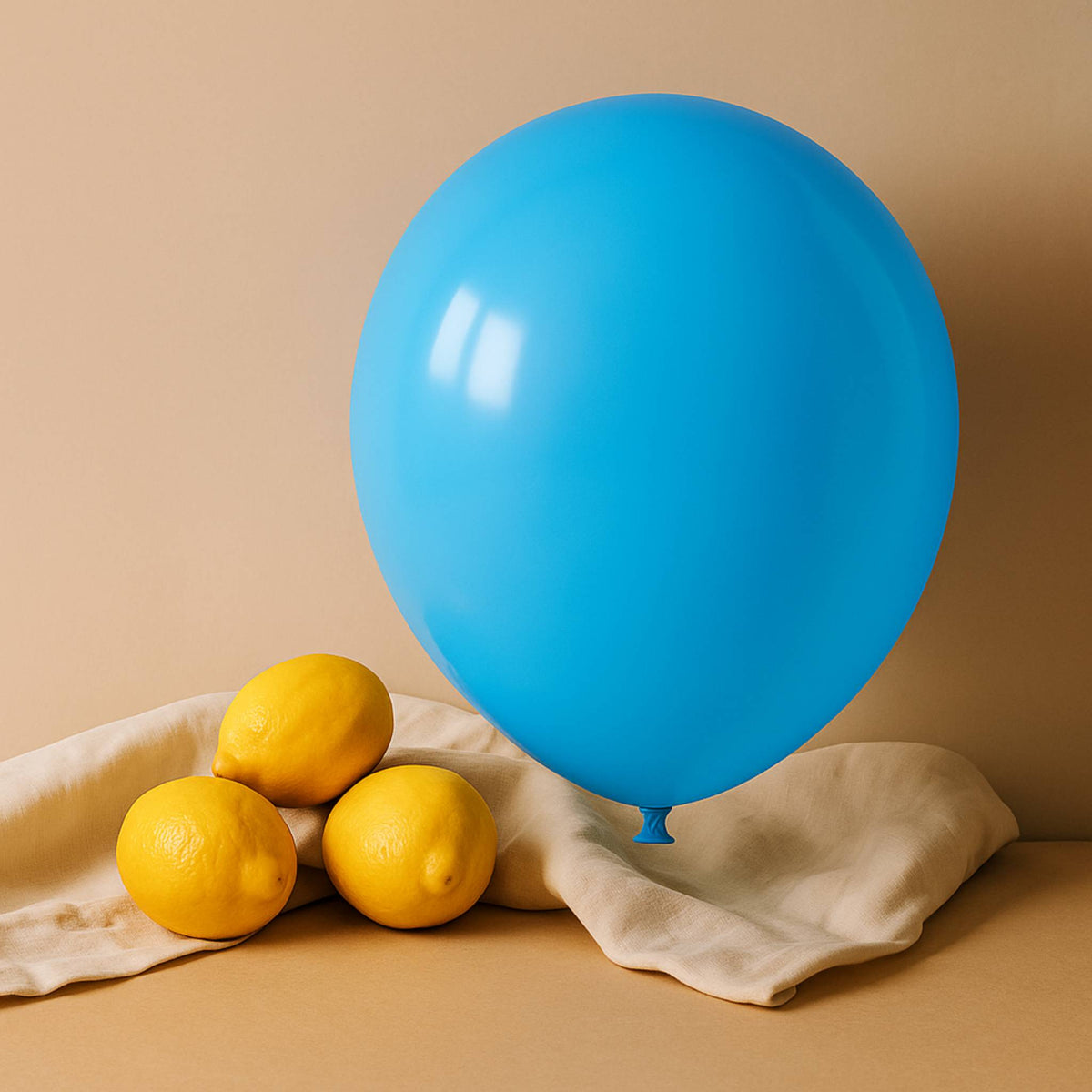 Blue 11 inch helium balloon and lemons on a beige surface with a beige background
