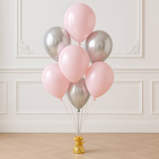 Bunch of pink and silver balloons on a stand against a white wall.