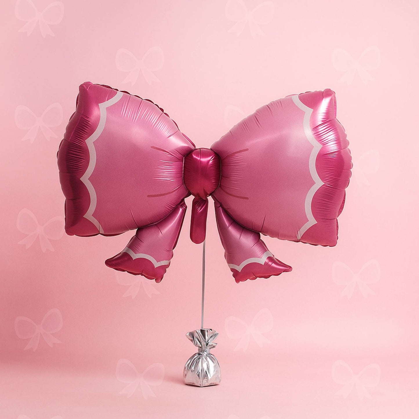 Pink bow-shaped balloon on a stand against a pink background