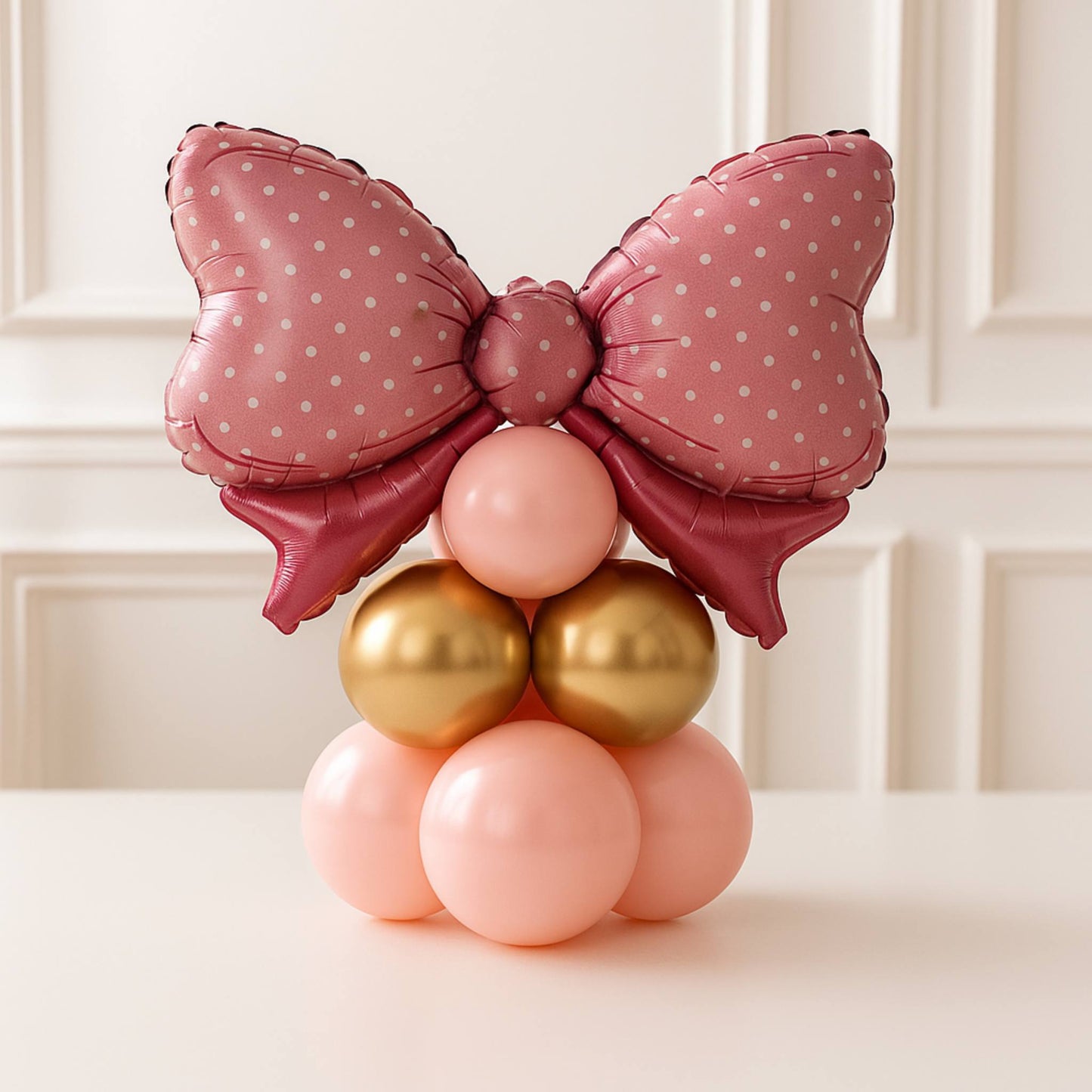 Balloon sculpture with a pink bow and colorful balloons on a white background