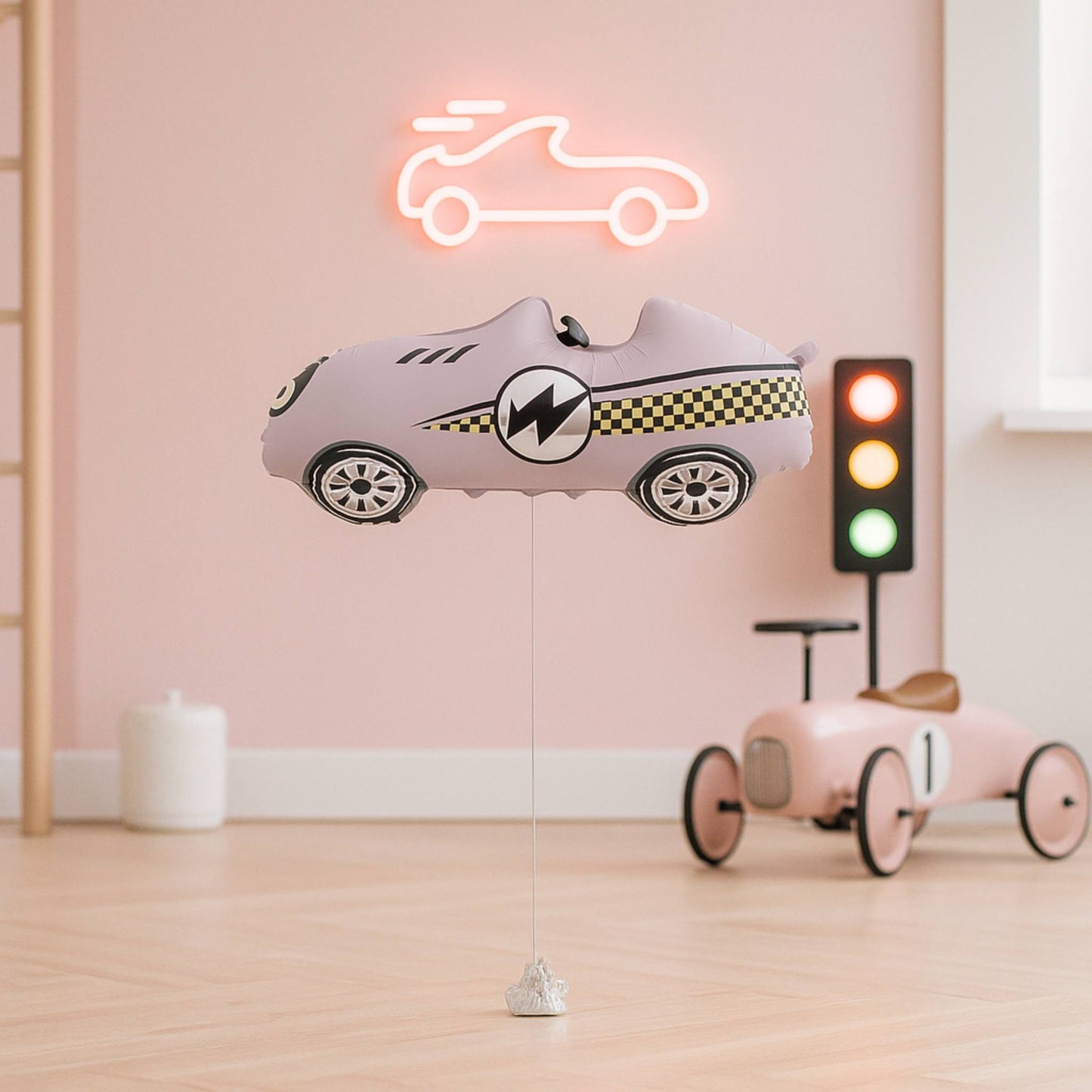Pink car-shaped clogs hanging from a string in a room with a pink wall, neon sign, and toy car.