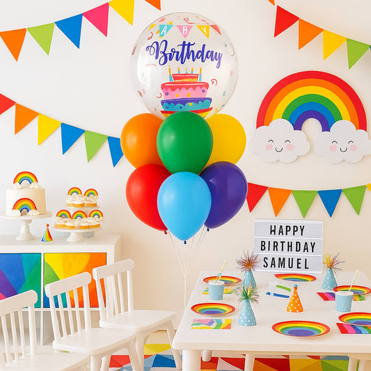 Colorful birthday party setup with balloons, rainbow decorations, and a cake.