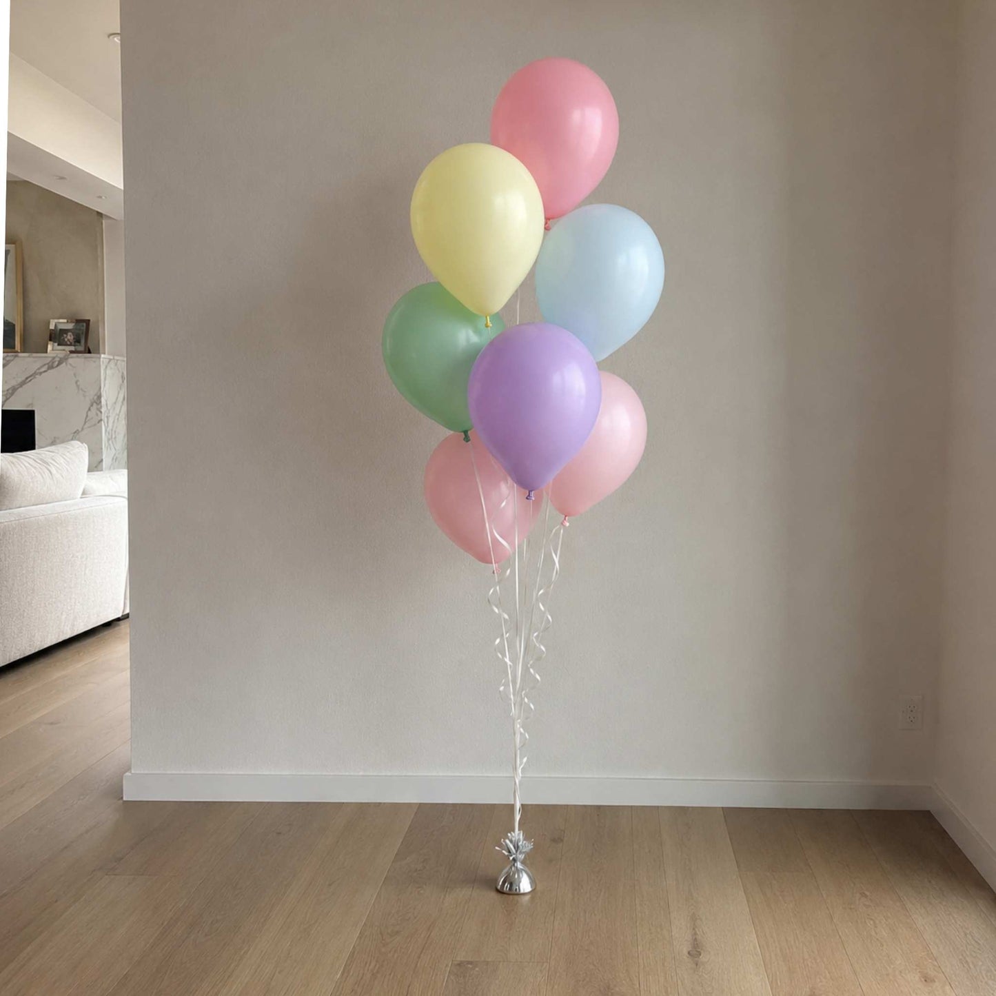 Bunch of pastel balloons tied together against a neutral wall.