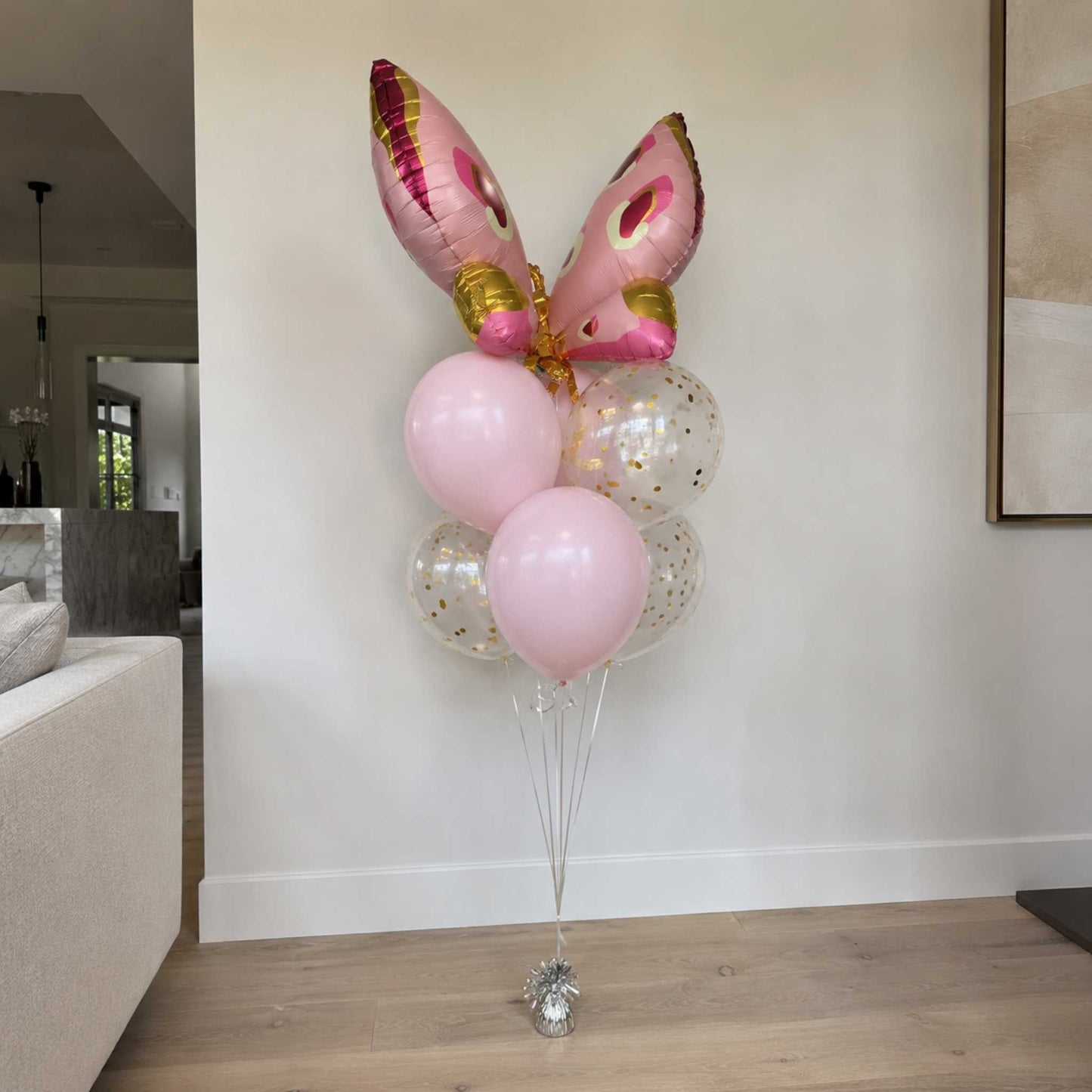 Bouquet of balloons with pink and gold accents in a living room setting.