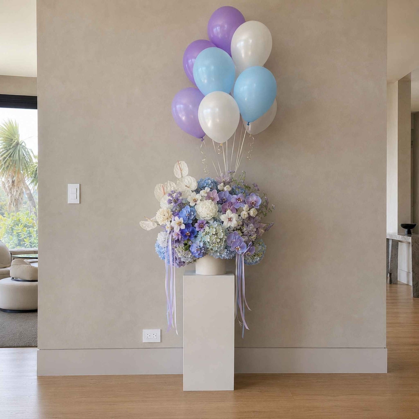 Floral arrangement with balloons on a pedestal in a room.