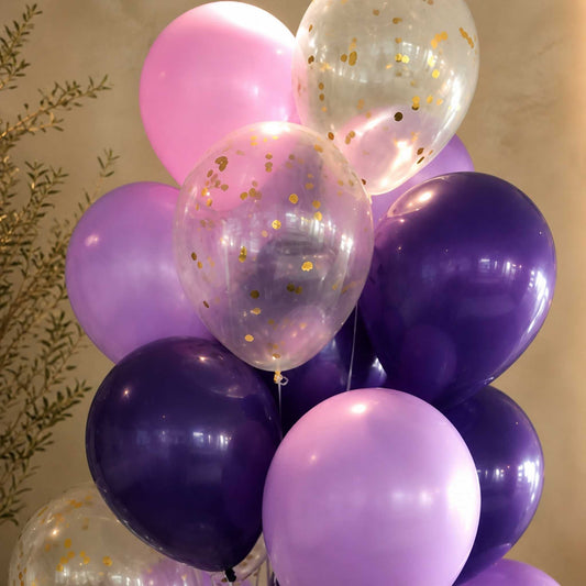 Bunch of balloons in pink, purple, and clear with gold confetti against a neutral background