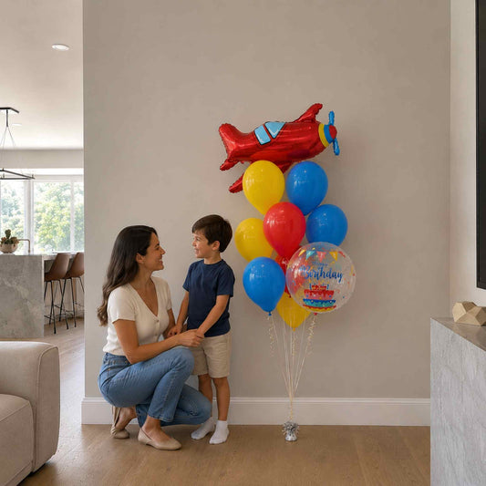 Woman and child with colorful balloons shaped like a red airplane in a living room.