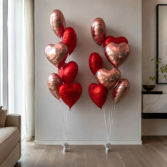 Heart-shaped balloons in red and rose gold on a light gray wall.