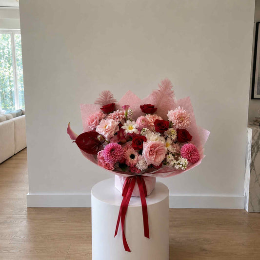 Bouquet of flowers on a white pedestal against a neutral wall.