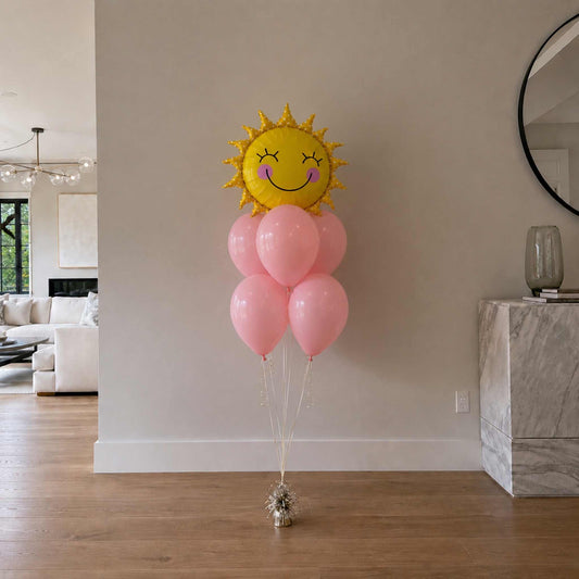Smiley sun helium balloon bouquet with pastel pink latex balloons styled in a modern luxury home with hardwood floors and neutral walls.