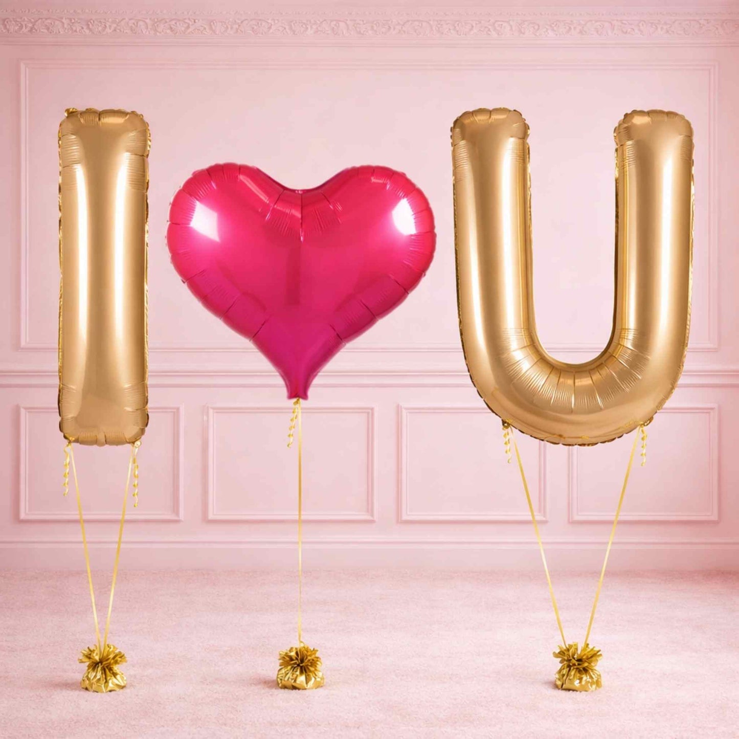Gold letter balloons spelling 'I U' with a pink heart balloon on a pink background