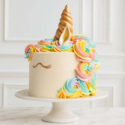 Colorful unicorn-themed cake with rainbow frosting and a white background