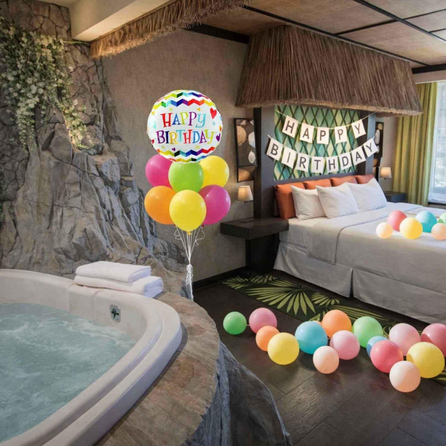 Birthday celebration in a room with balloons, a hot tub, and 'Happy Birthday' decorations.