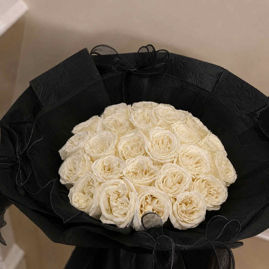 Bouquet of white roses in a black wrap with a neutral background