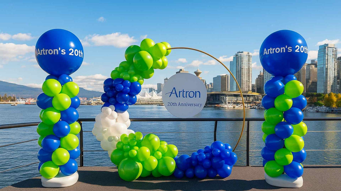 Balloon arch with 'Artron's 20th' on a waterfront with city skyline in the background