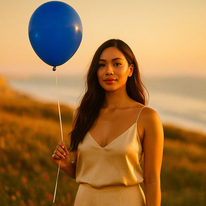 Woman holding a blue balloon against a sunset backdrop