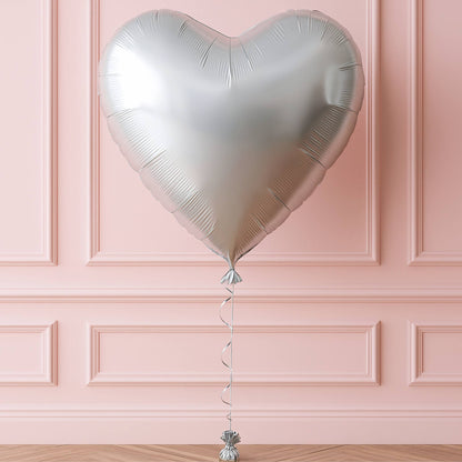 Silver heart-shaped balloon against a pink paneled wall