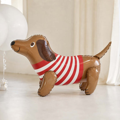 Inflatable dachshund balloon with a red and white striped shirt on a light background