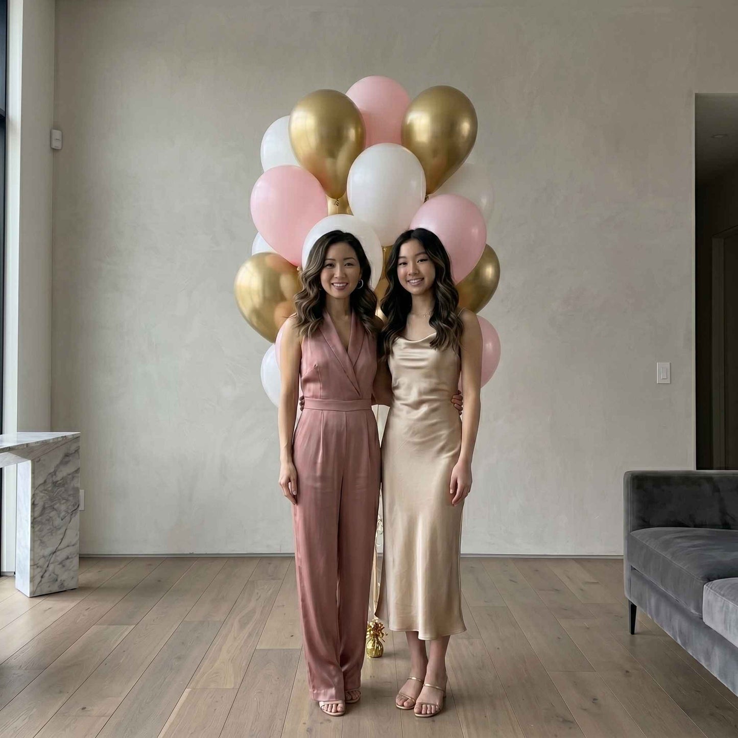 pink, white, and chrome gold balloons in an apartment with woman and daughter standing in front 