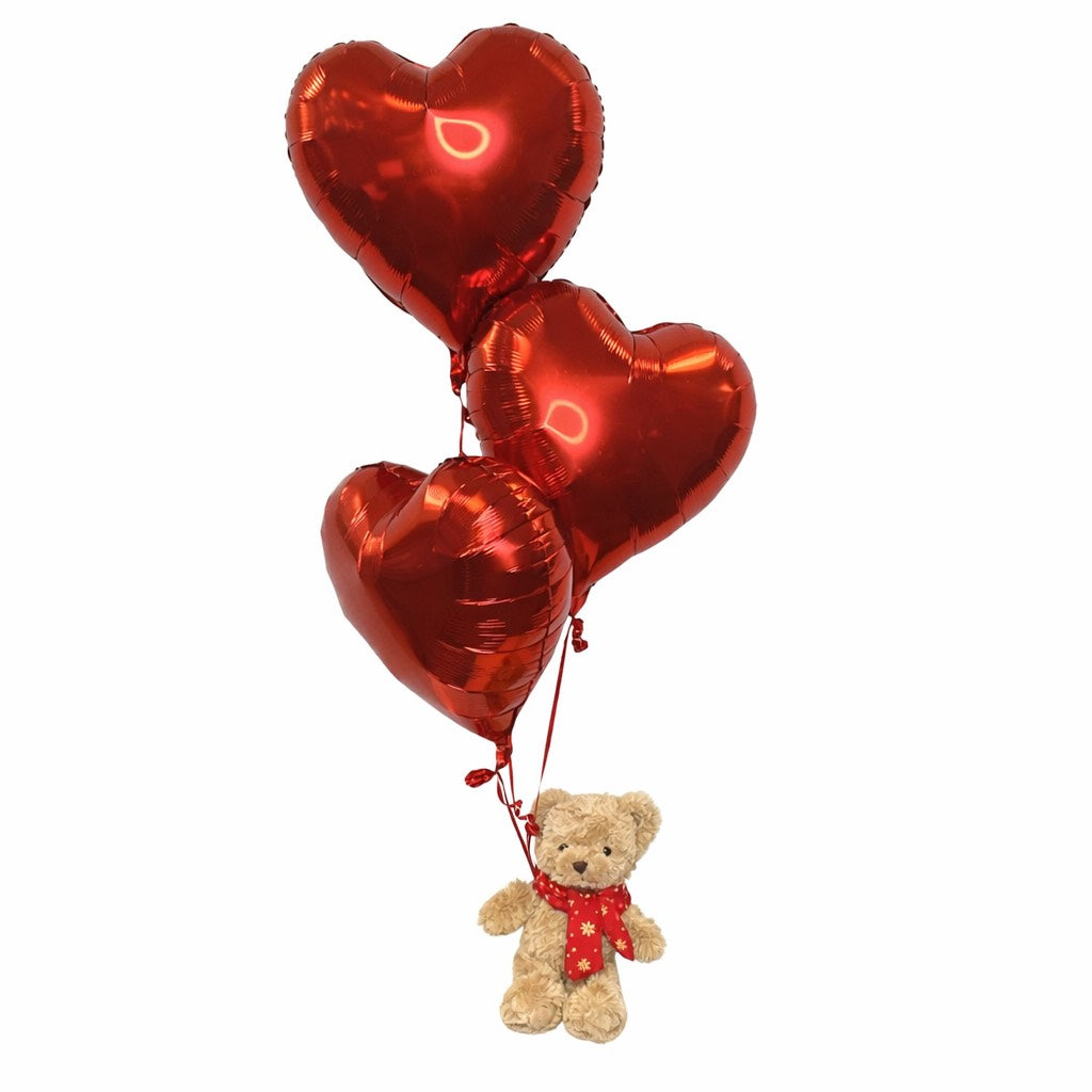 Red heart-shaped balloons with a teddy bear attached on a white background