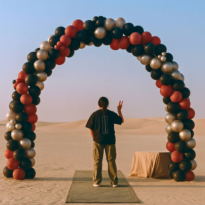 Person standing in front of a colorful balloon arch in a desert setting