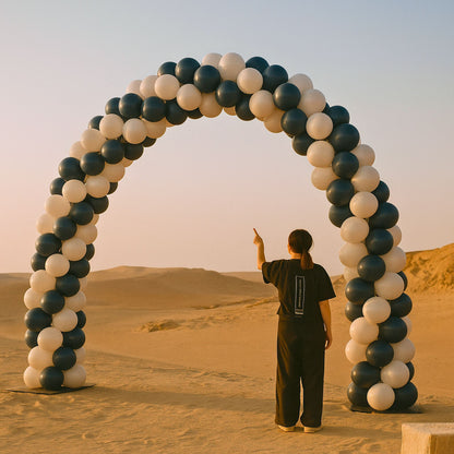Person standing under a large arch made of balloons in a desert setting