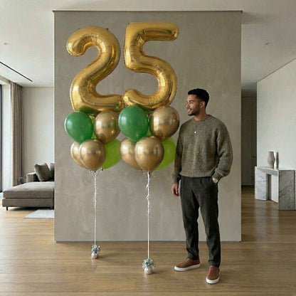 Man standing next to a large '25' balloon arrangement in a modern living room.