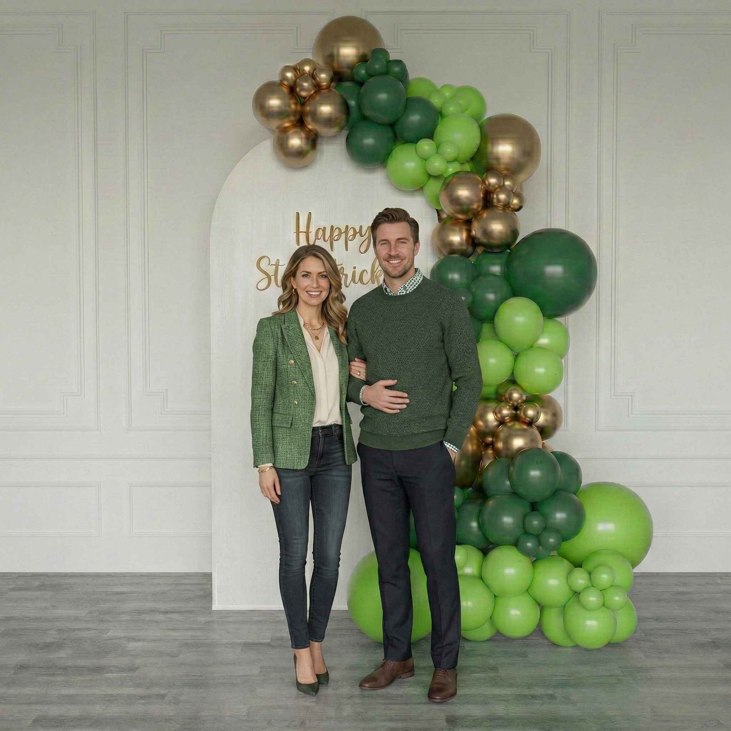 Couple posing in front of a St. Patrick's Day balloon arch with 'Happy St. Patrick's Day' text.