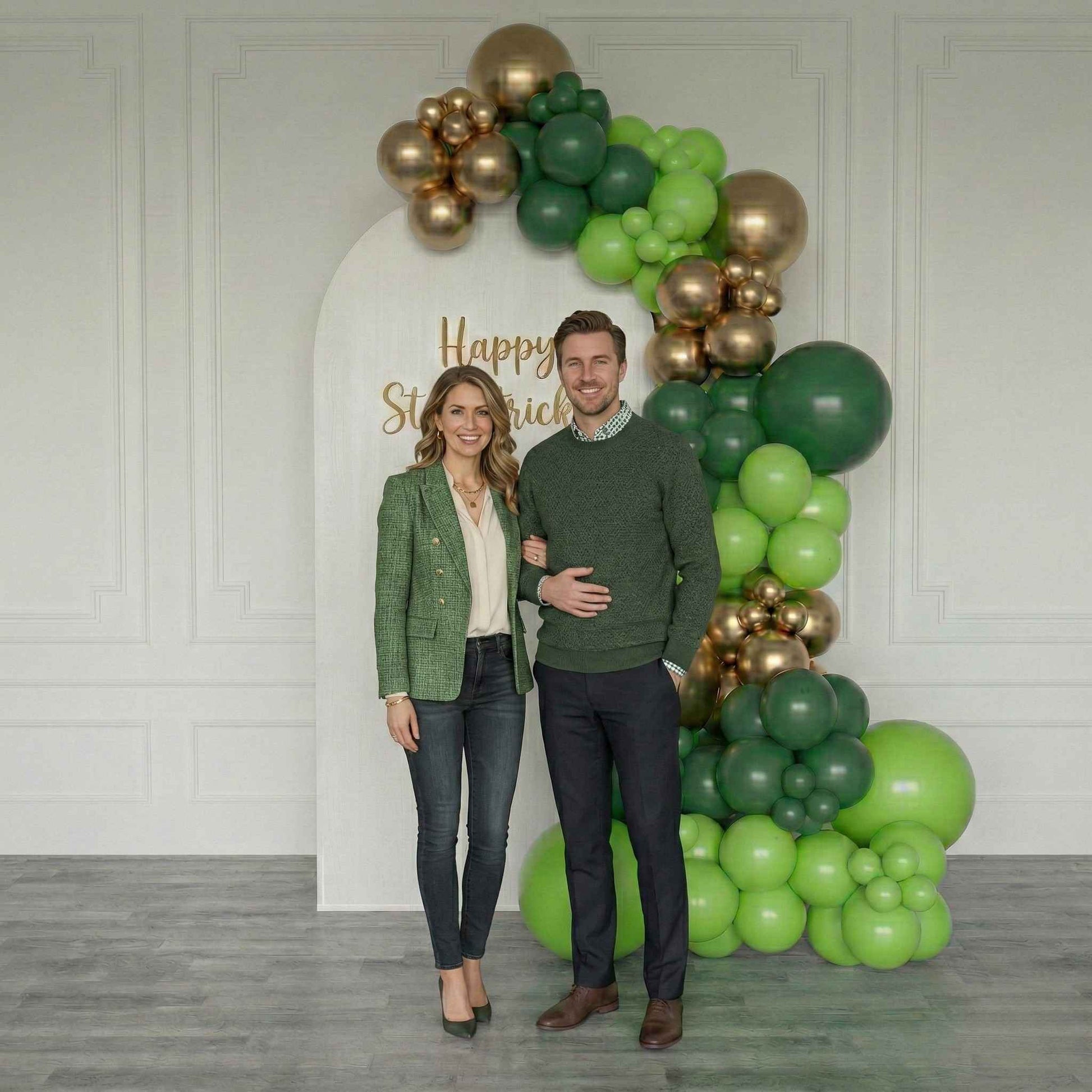 Couple posing in front of a St. Patrick's Day balloon arch with 'Happy St. Patrick's Day' text.