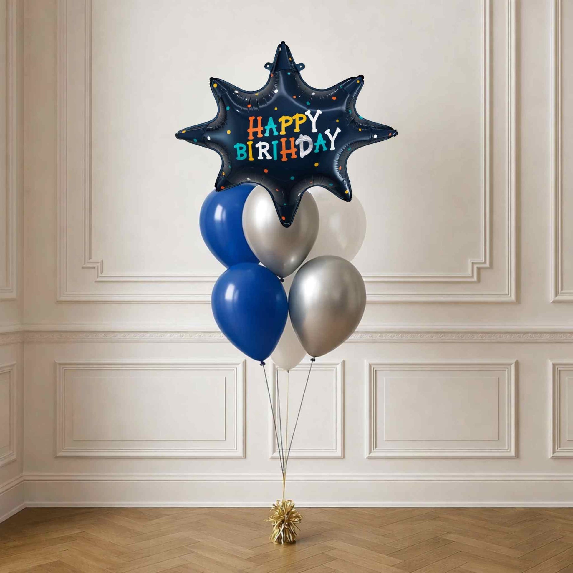Star-shaped 'Happy Birthday' balloon with blue and silver balloons against a white wall.