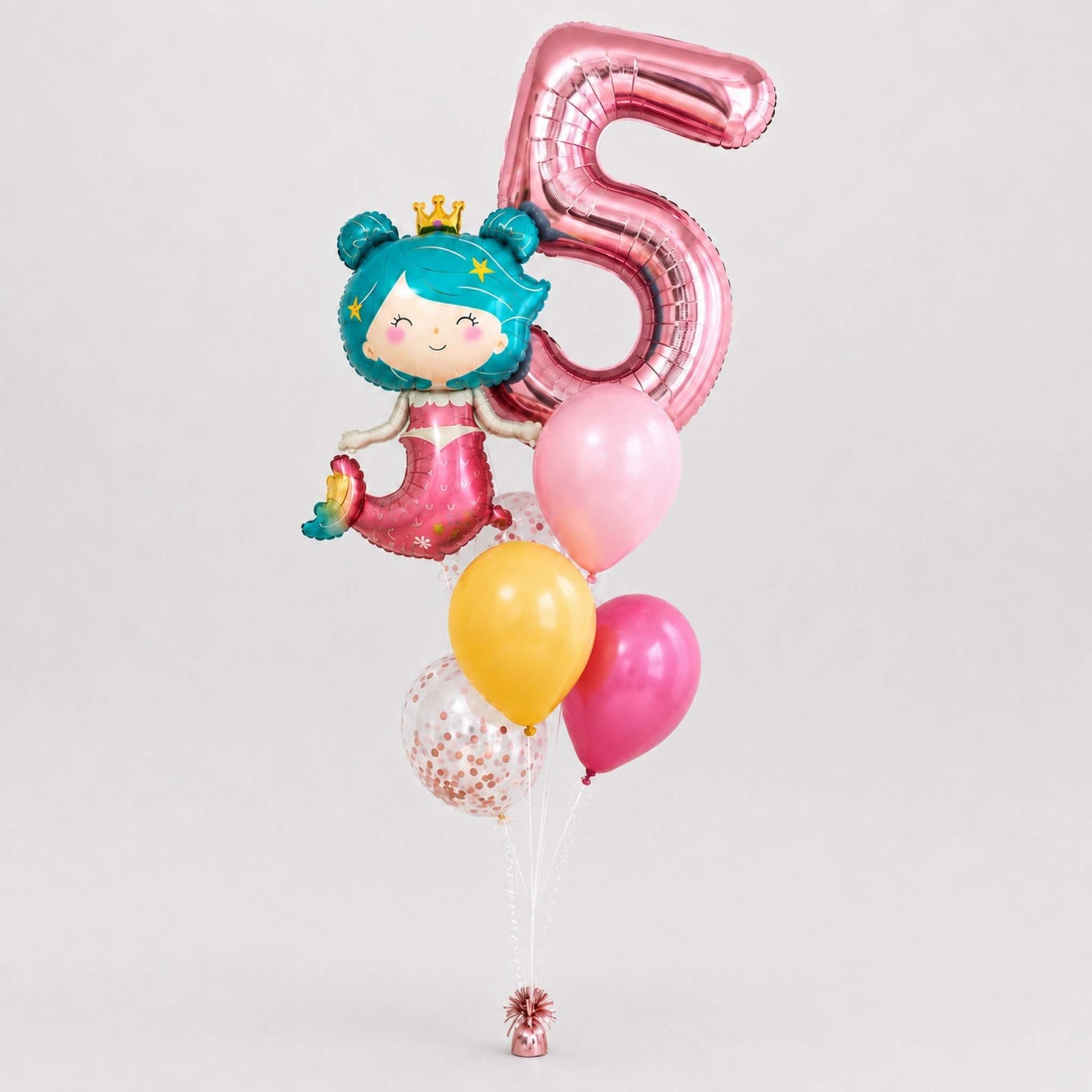 A birthday balloon bouquet featuring a large metallic pink foil balloon shaped like the number 5, a mermaid character balloon with teal hair and a pink dress, plus several latex balloons in pink, yellow, and clear with confetti, set against a plain light gray background.