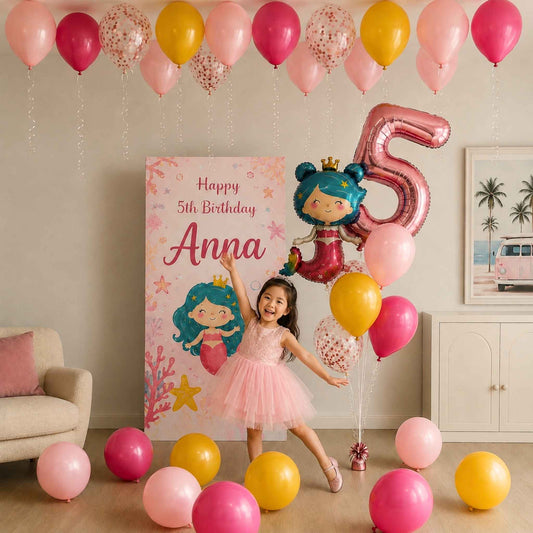A young girl in a pink tutu stands in a decorated room with pink, yellow, and clear balloons, a large metallic pink '5' balloon, a cartoon mermaid graphic, and a personalized 'Happy 5th Birthday Anna' banner.