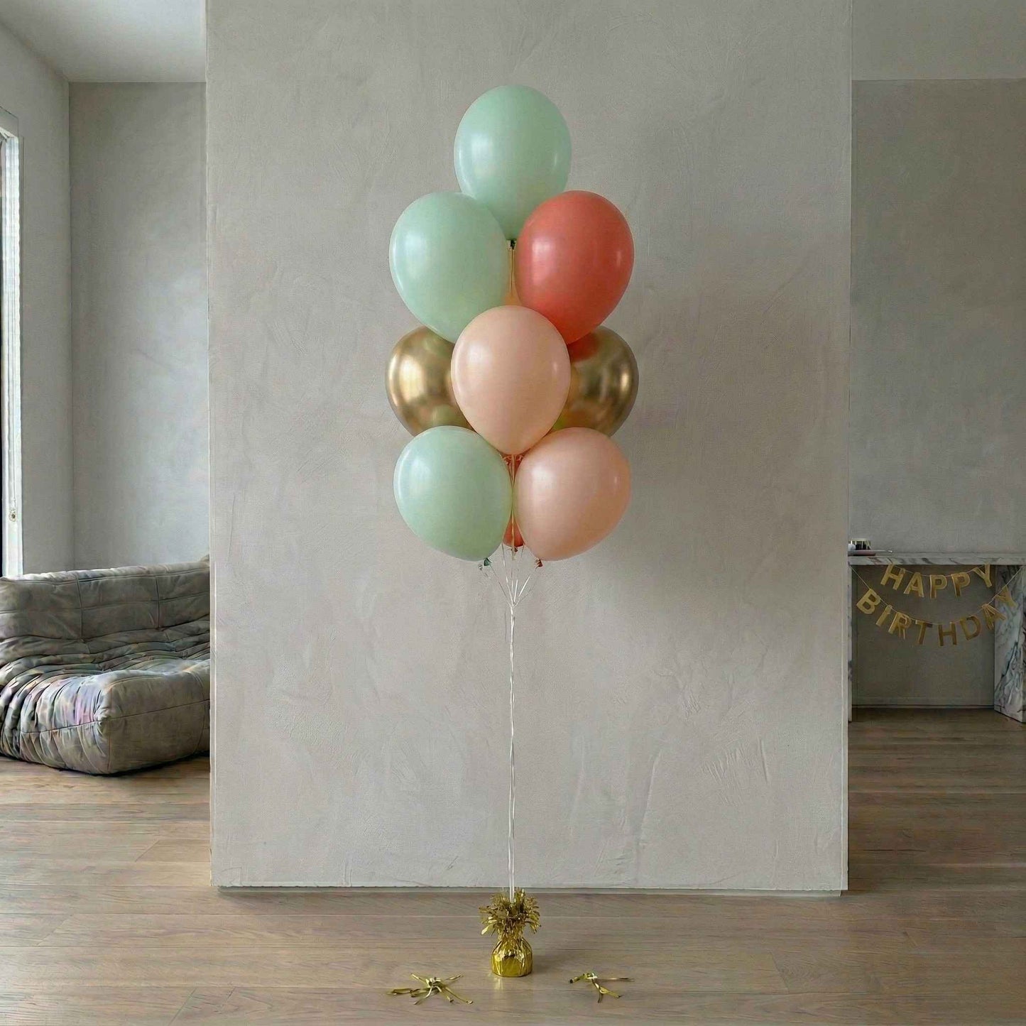 Bouquet of colorful balloons against a plain wall with 'Happy Birthday' banner in the background.