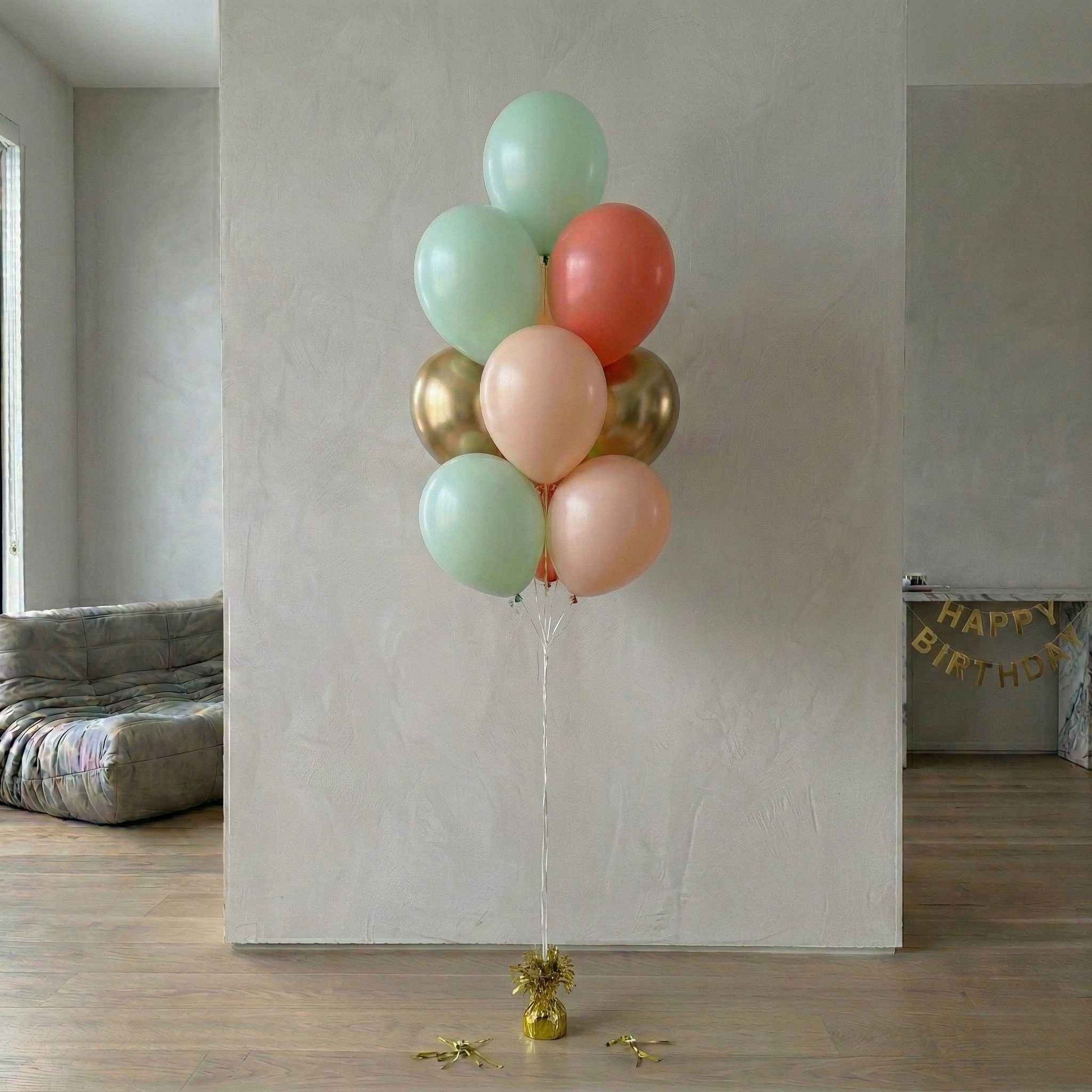 Bouquet of colorful balloons against a plain wall with 'Happy Birthday' banner in the background.